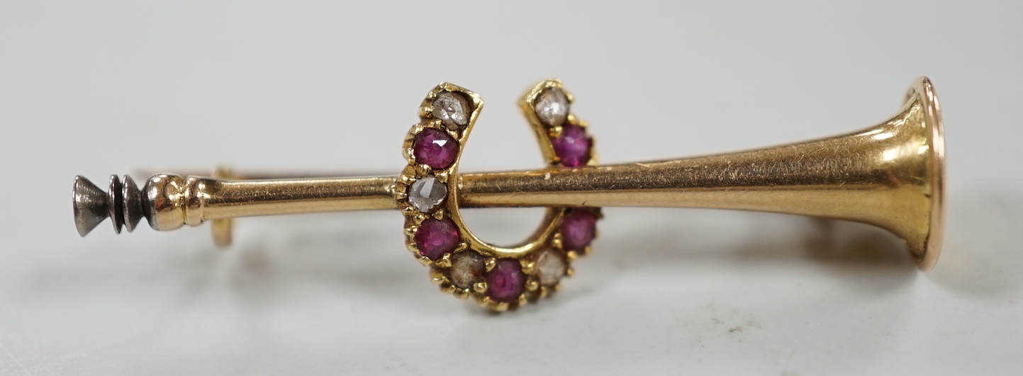 An Edwardian yellow metal, ruby and diamond set hunting horn and horseshoe brooch, 37mm, gross weight 2.6 grams.